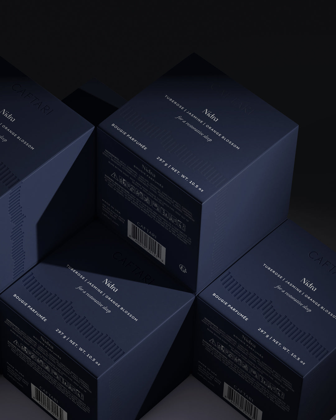 Stack of dark blue boxes with 'Nudie' branding on a black background