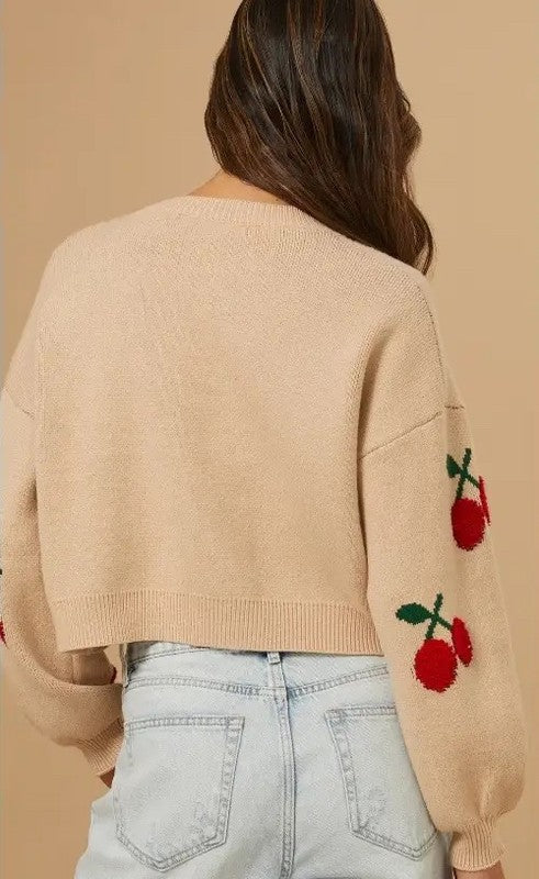 Beige sweater with cherry designs on a beige background
