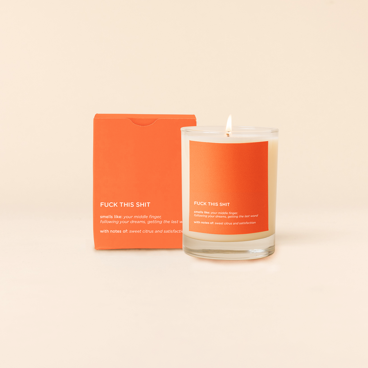 Candle with orange packaging on a beige background