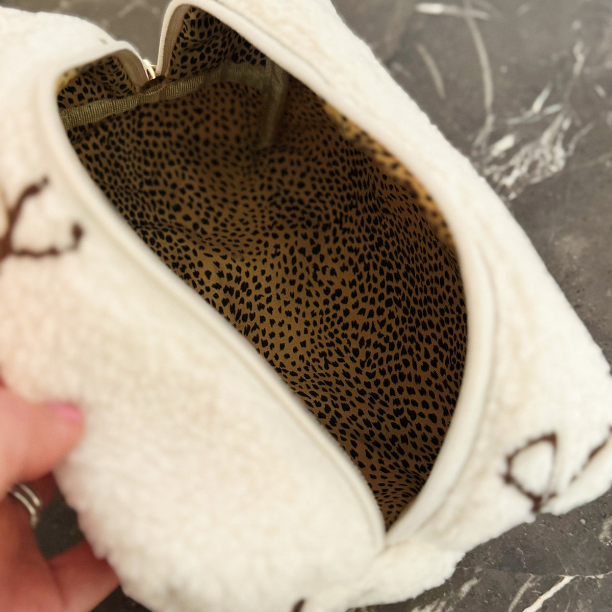 Close-up of a white shoe with a leopard print pattern inside, held by a hand.
