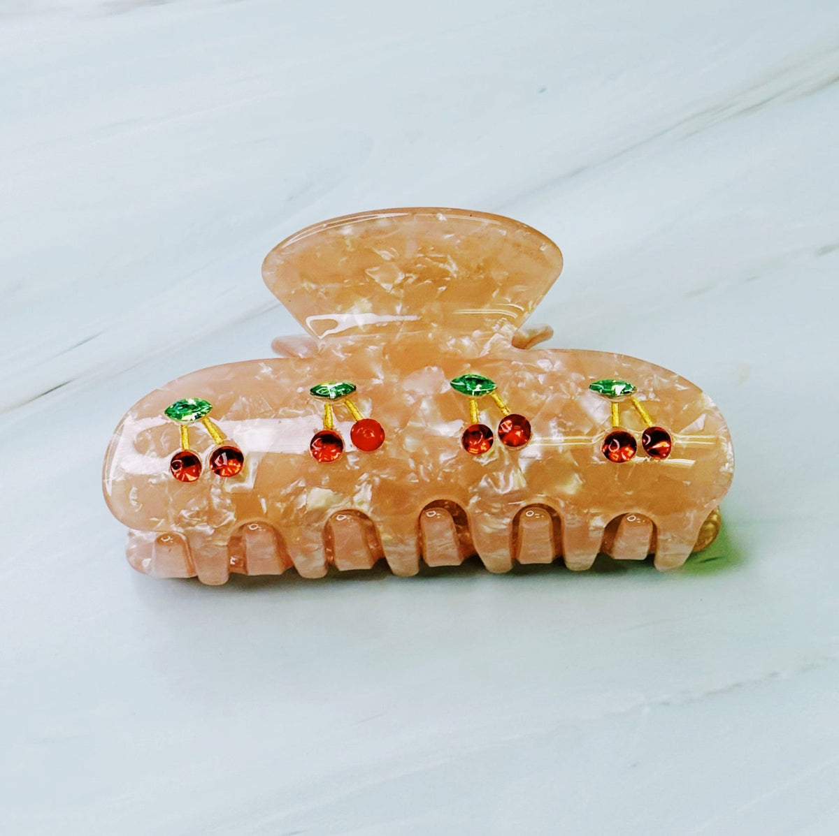 Decorative hair clip with cherry designs on a light background