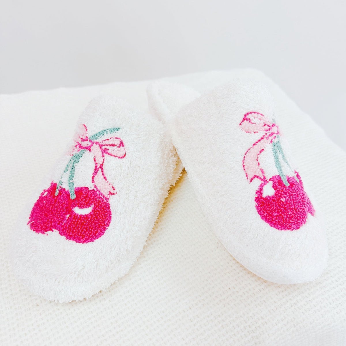 white slippers with pink cherries and bows on a white background