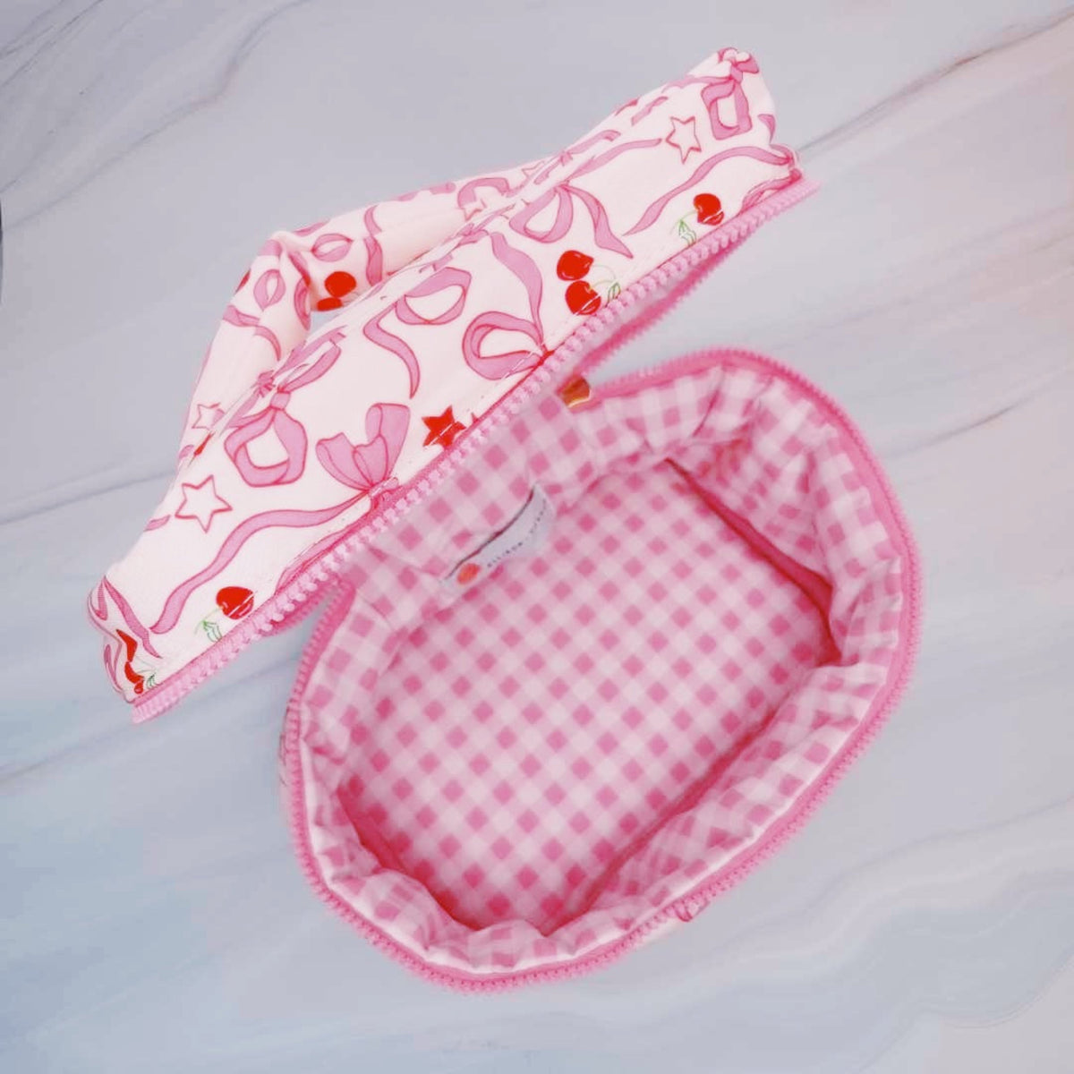Pink baby bib with checkered pattern on a light gray background