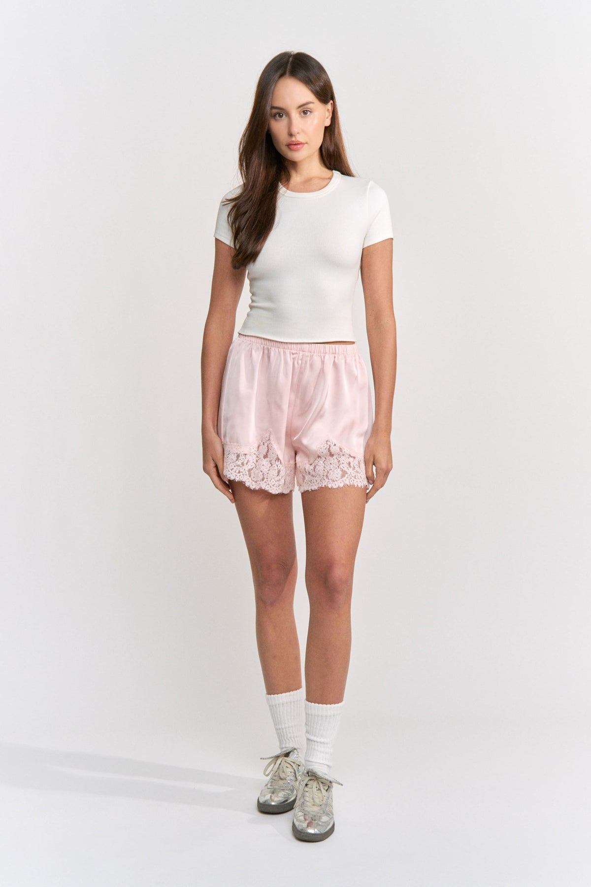 Woman wearing a white t-shirt and pink shorts on a white background
