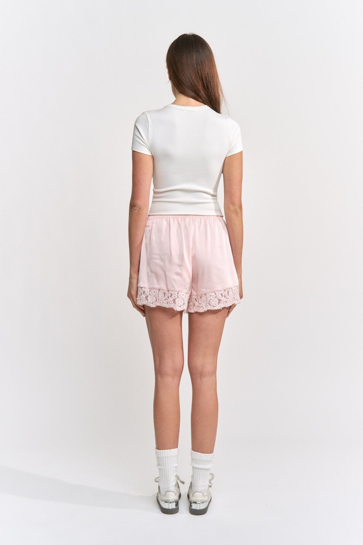 Woman wearing a white top and pink shorts on a white background