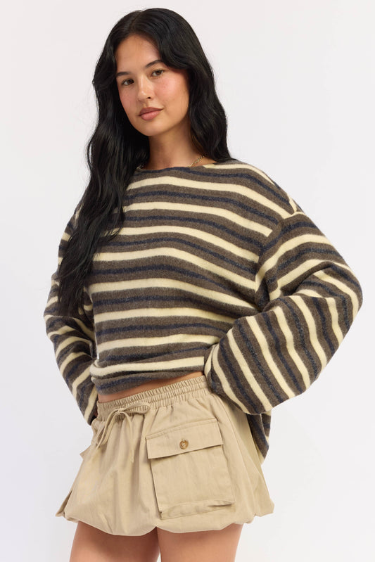 A woman modeling a fuzzy knit long-sleeve crop top with horizontal dark brown and beige stripes, paired with beige shorts, against a plain white studio background.