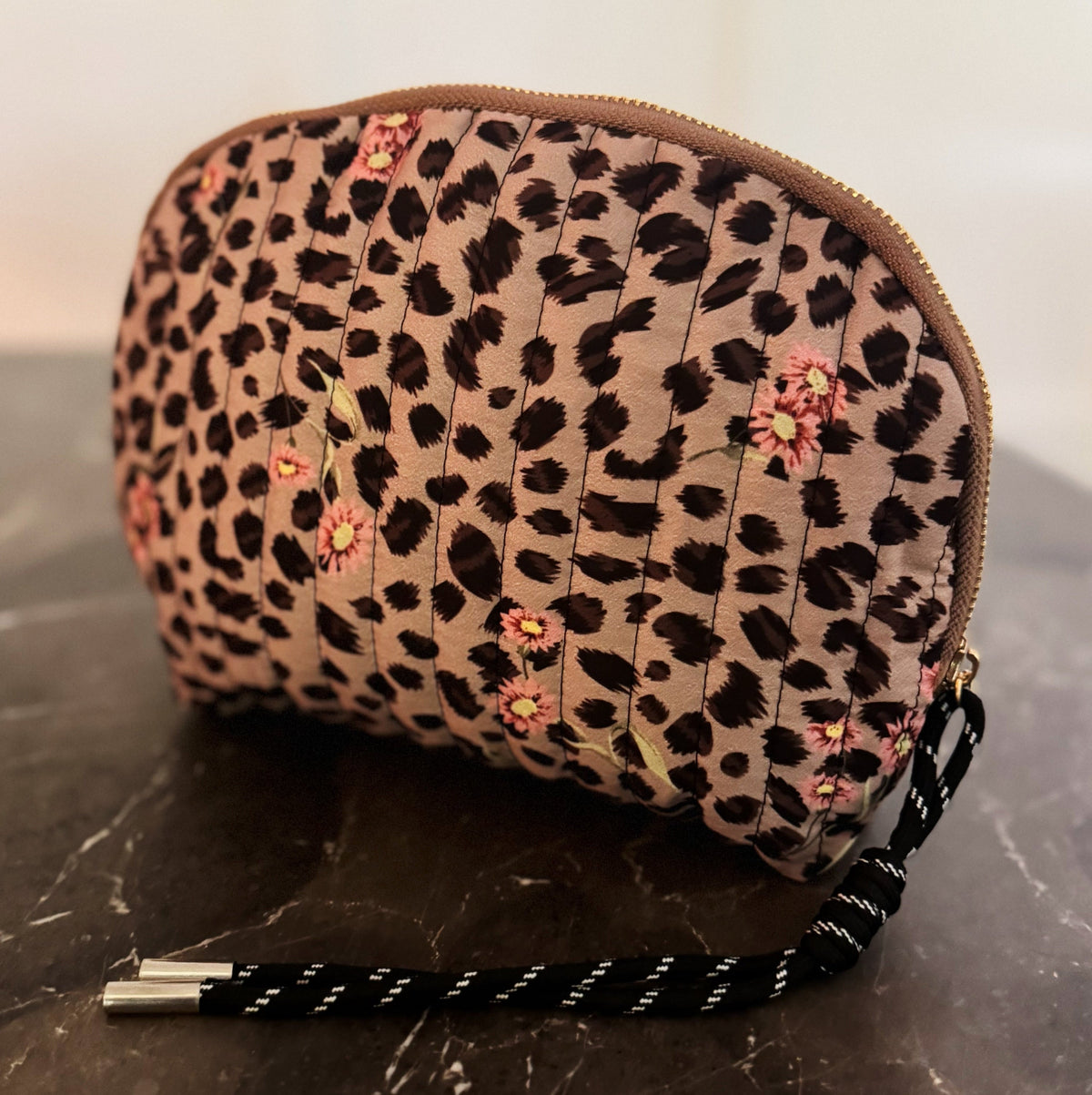 Leopard print pouch with floral accents on a marble surface
