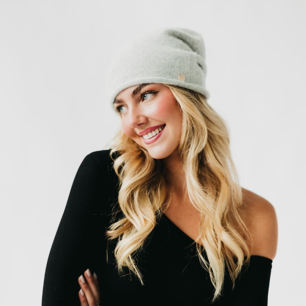 Woman wearing a gray beanie and black top on a white background