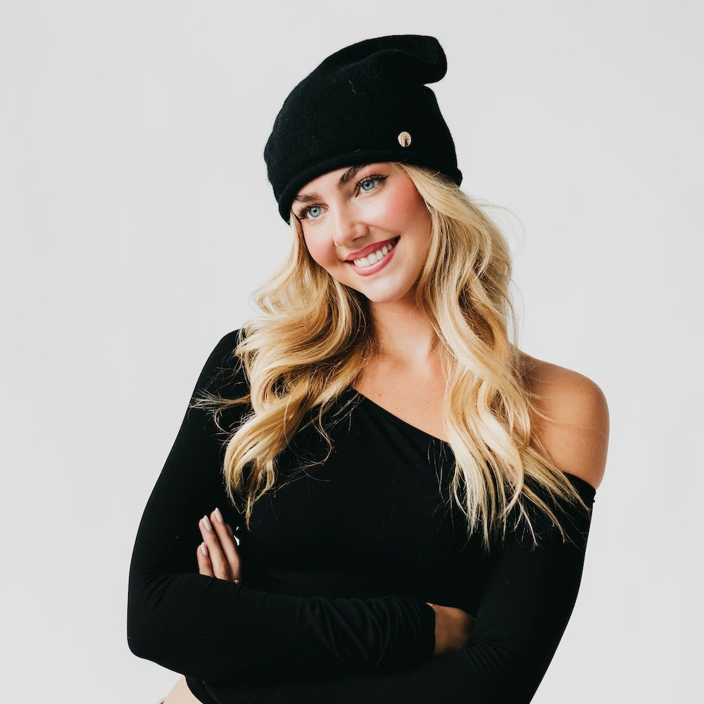 Woman wearing a black beret and black top against a light gray background