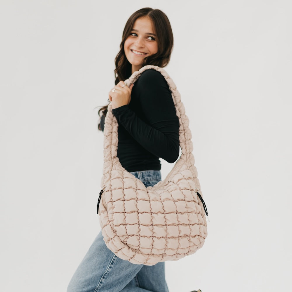 Woman holding a textured beige handbag against a white background