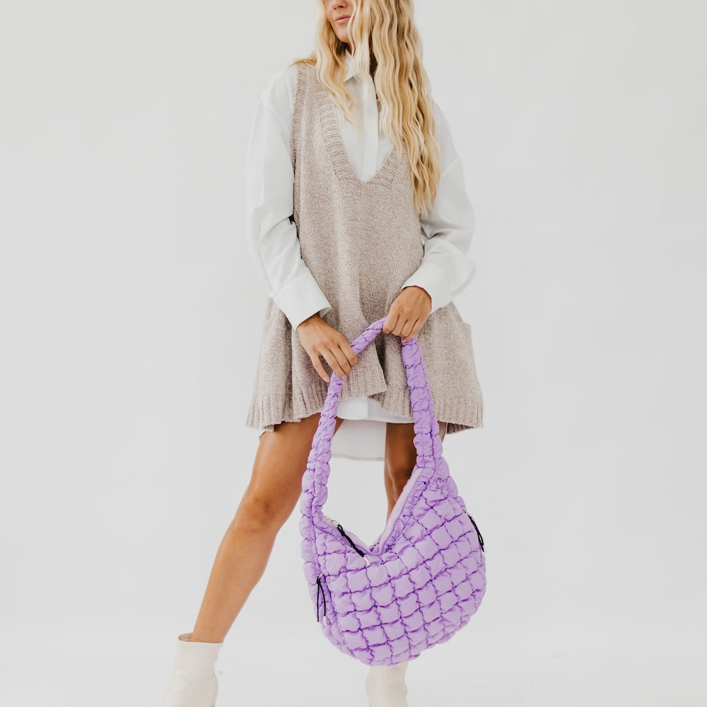 Woman holding a purple textured handbag against a plain background