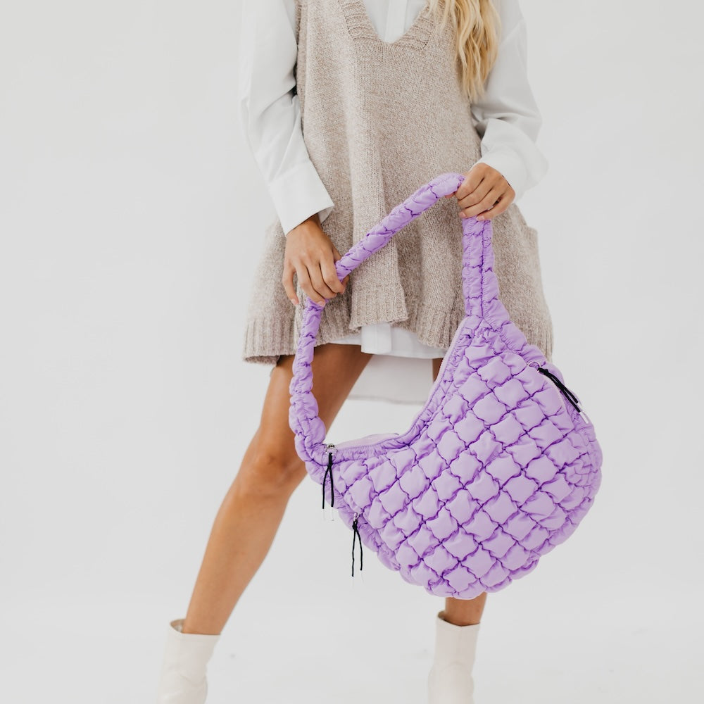 Person holding a purple textured bag against a plain background