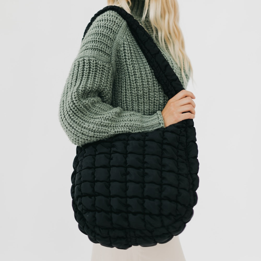 Person holding a black textured bag with a plain background