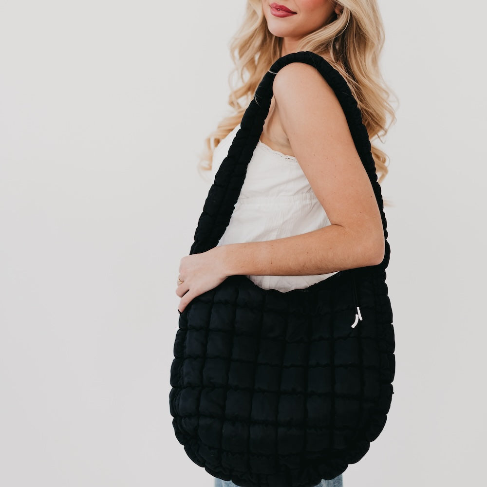 Person holding a black textured bag against a plain background