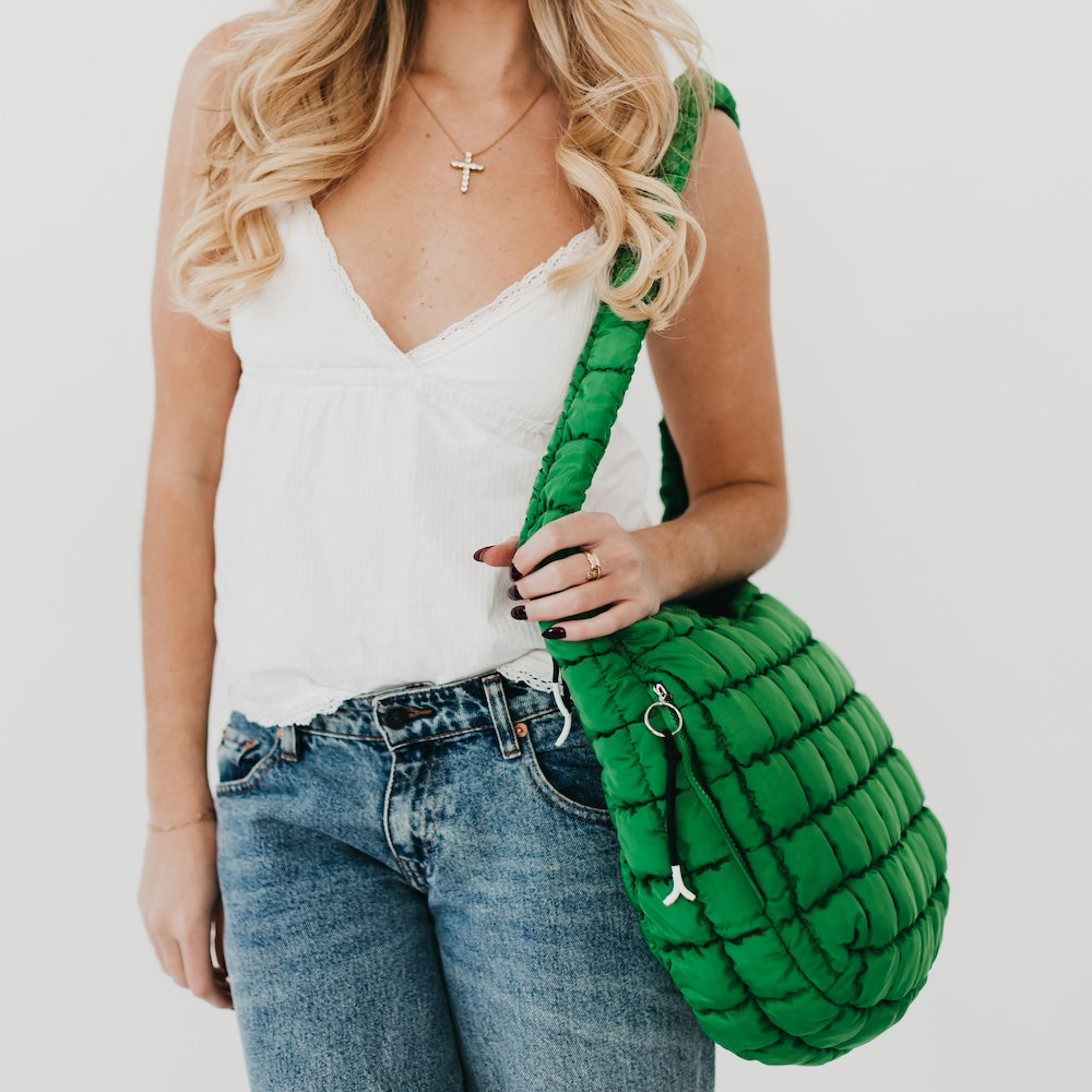 Woman holding a green textured handbag against a plain background