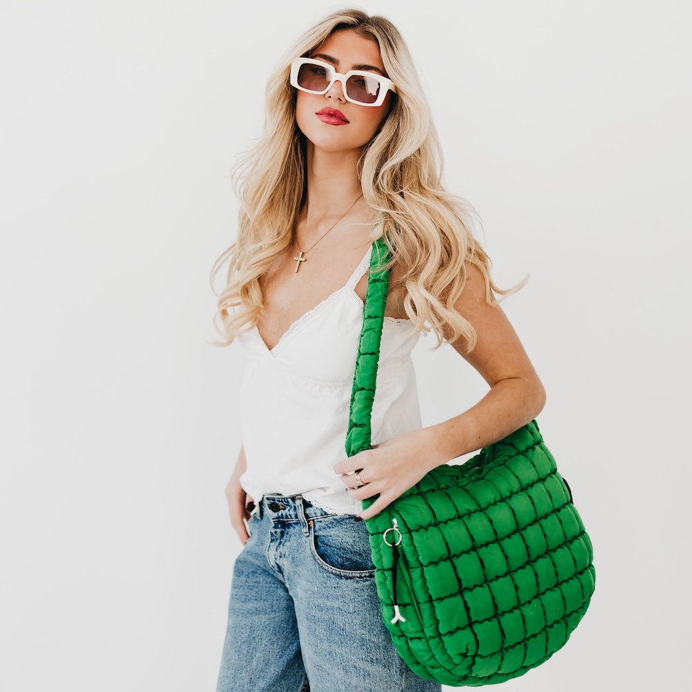 Woman holding a green quilted handbag against a white background