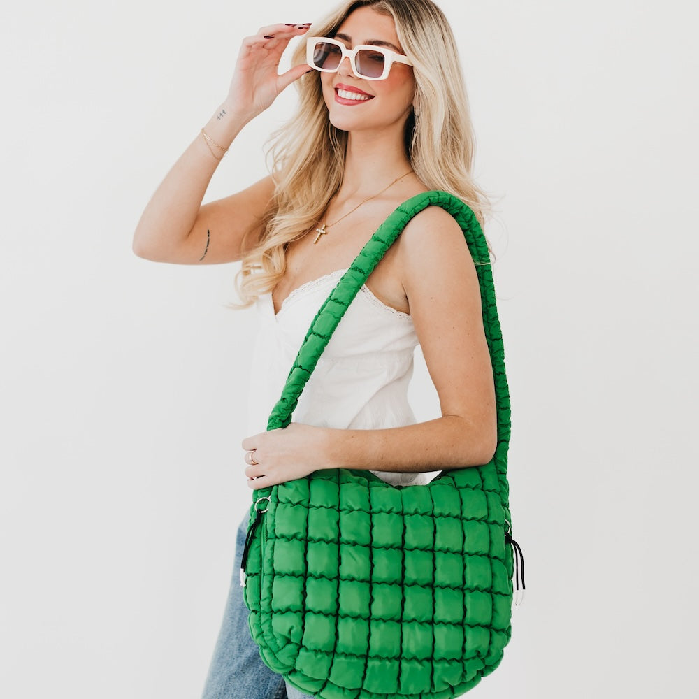 Woman holding a green quilted bag against a white background