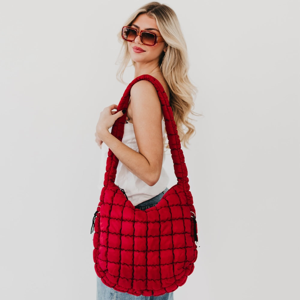 Woman holding a red quilted handbag against a white background