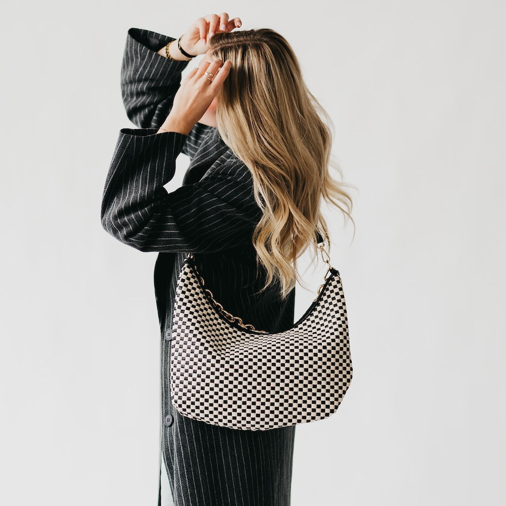 Person holding a black and white checkered bag against a plain background