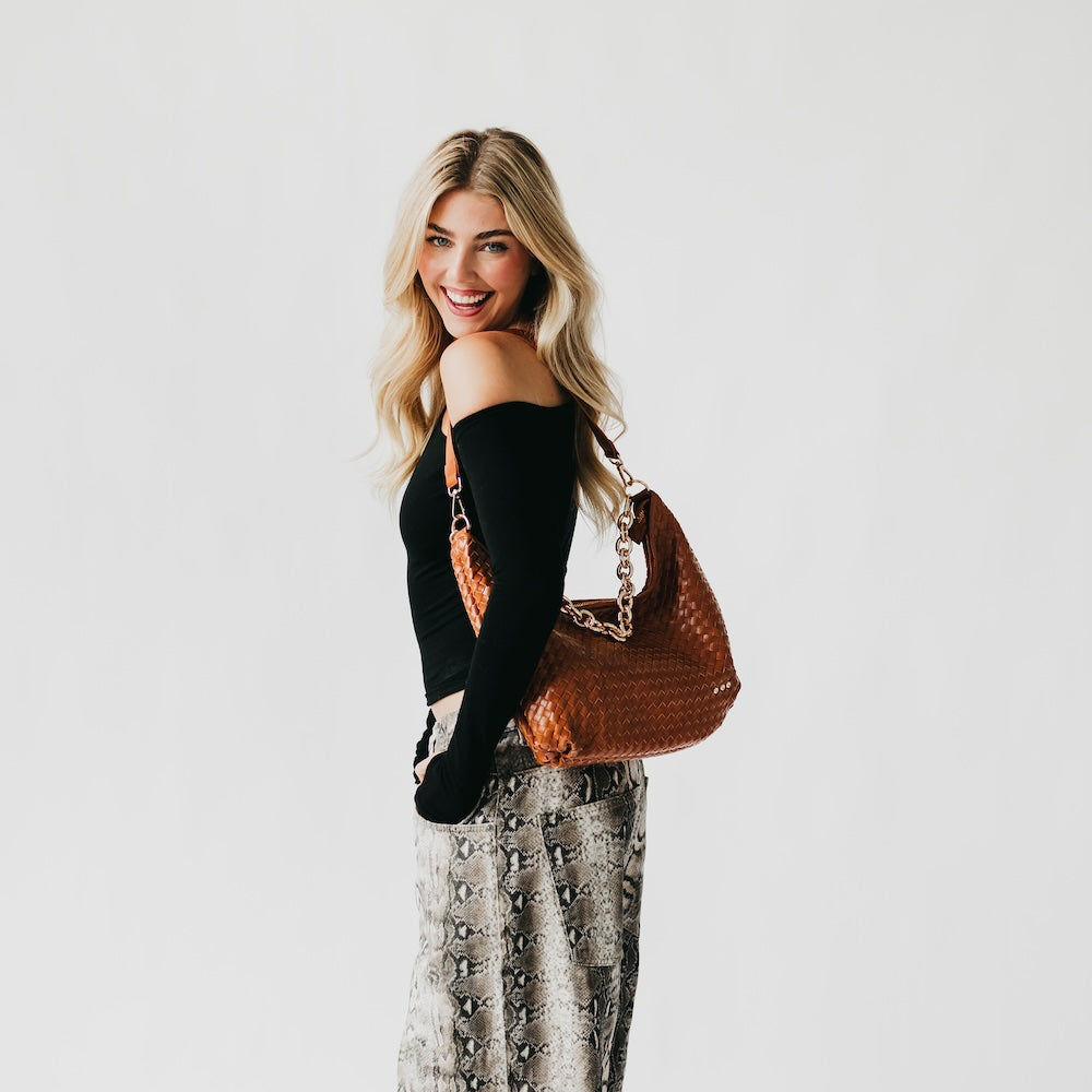 Woman holding a brown handbag against a white background