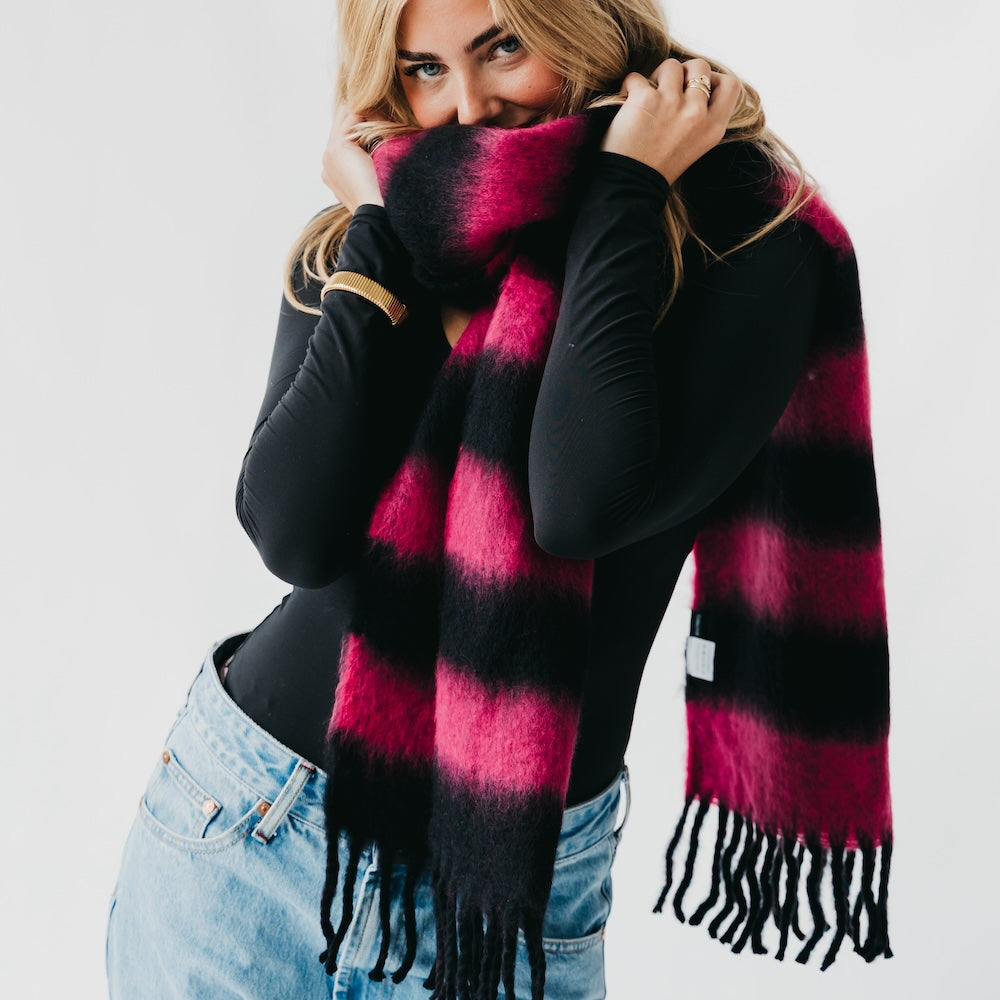 Woman wearing a black and pink plaid scarf with a white background