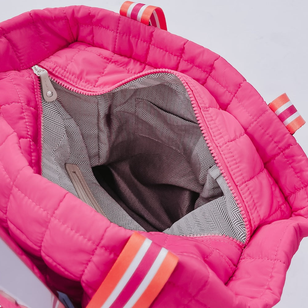 Close-up of a pink quilted jacket with orange accents on a light gray background