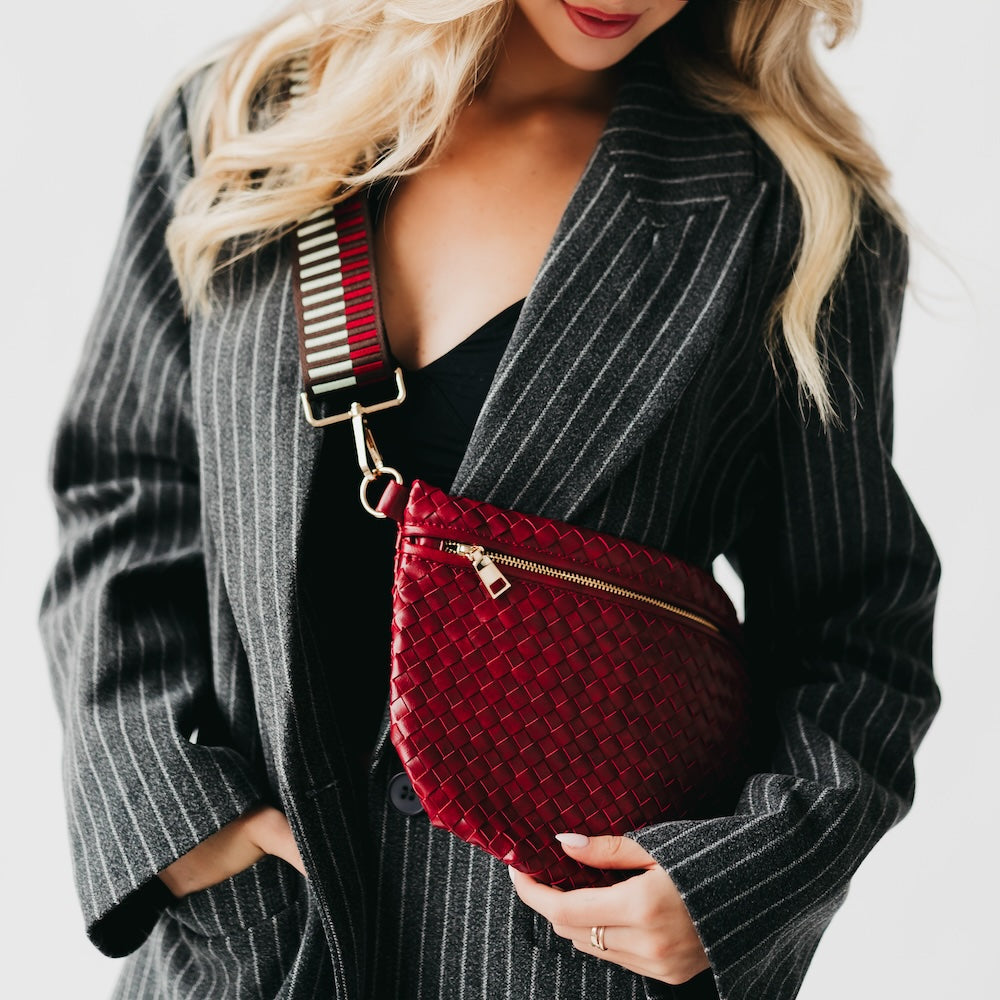 Woman holding a red woven handbag against a neutral background