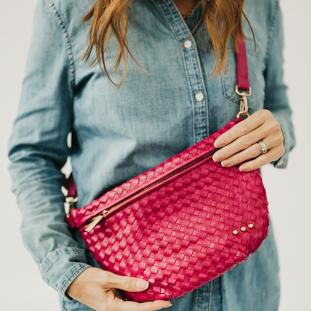 Person holding a pink woven handbag vegan leather with a blurred background