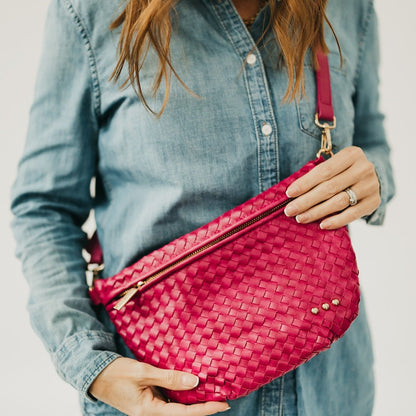 Person holding a pink woven handbag vegan leather with a blurred background