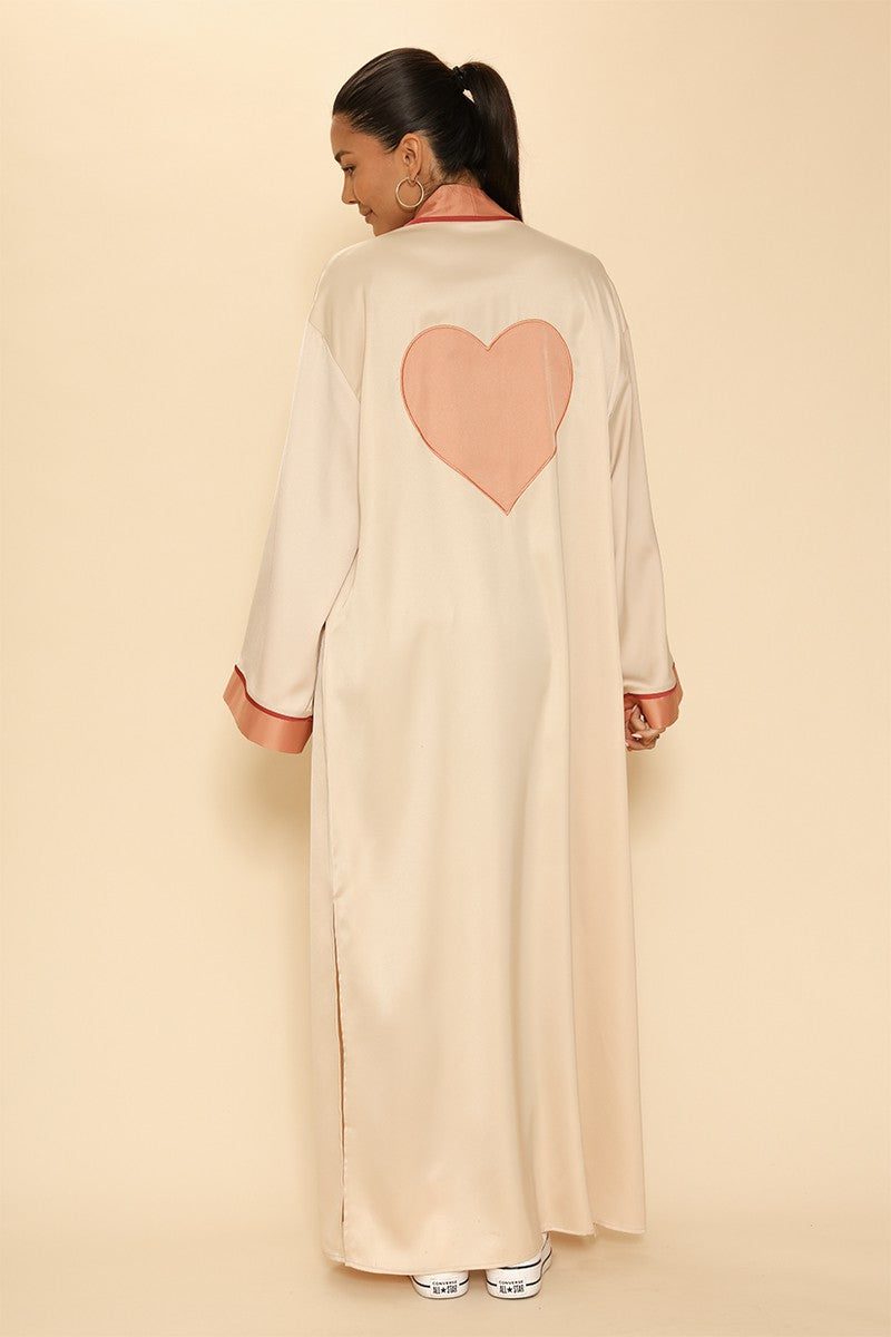 Woman wearing a beige long dress with a pink heart design on a beige background
