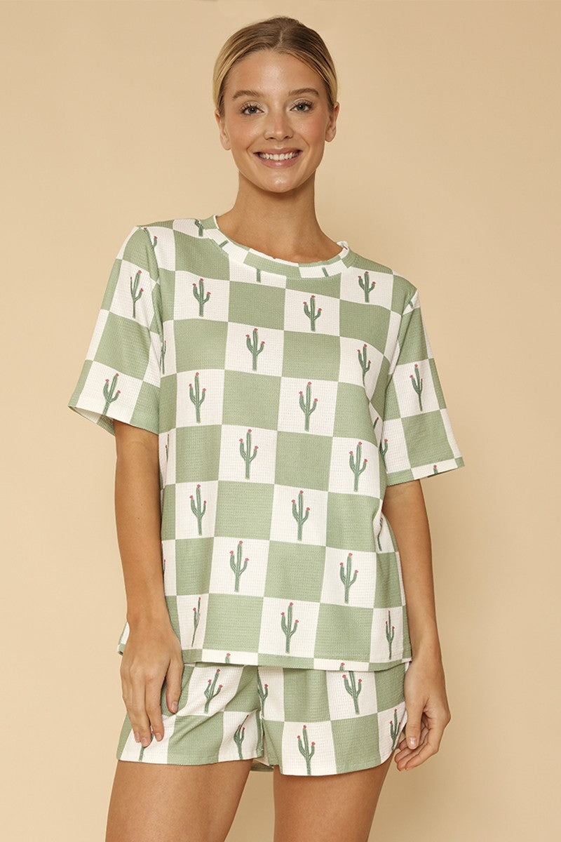 Woman wearing a green and white checkered outfit with cactus pattern on a beige background
