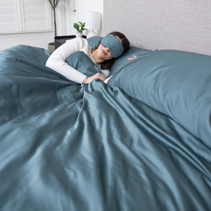 Person lying in bed with blue bedding and a matching eye mask. Luxurious Organic Bamboo Duvet Cover Set