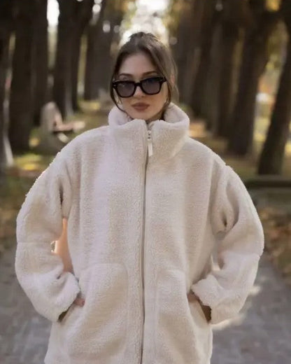 Person wearing a fluffy white coat and sunglasses outdoors.