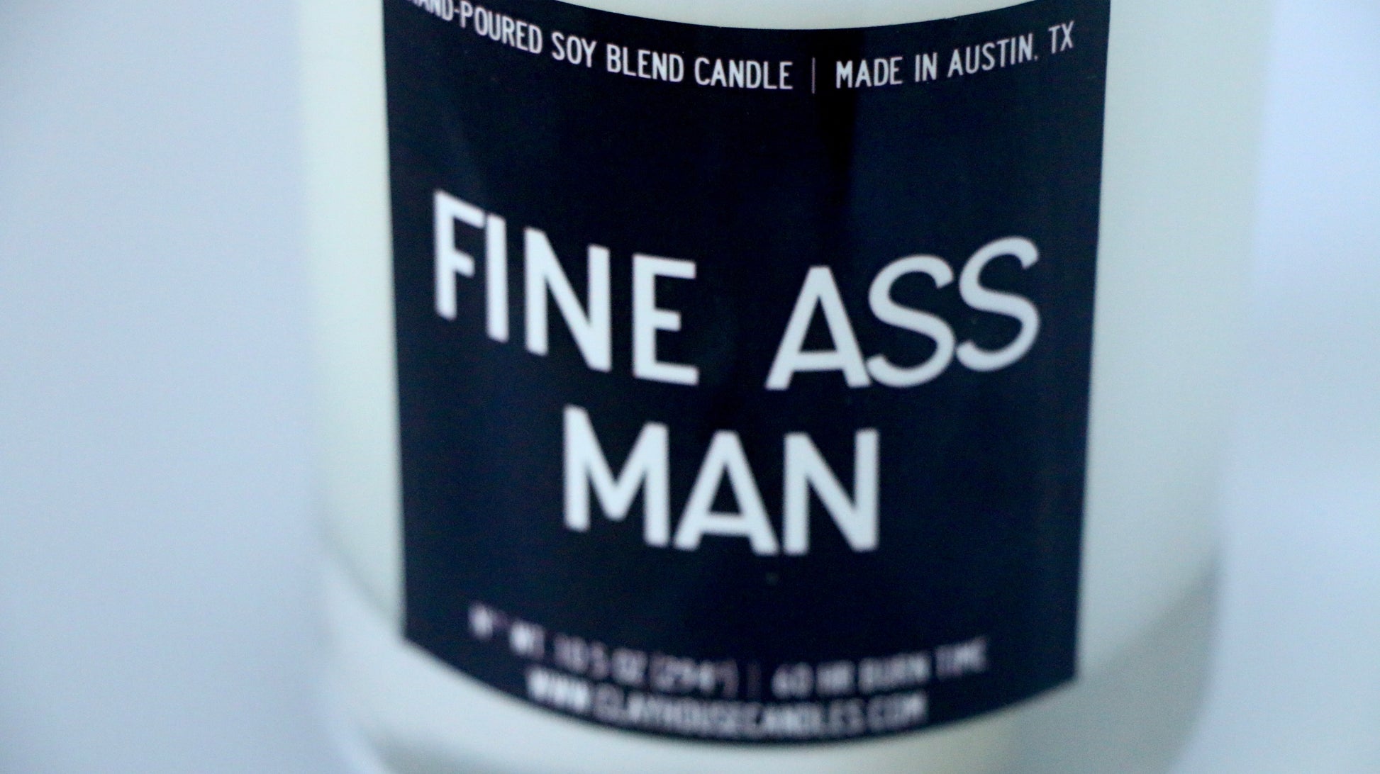 Candle with a label reading 'FINE ASS MAN' on a white background