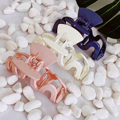 Set of colorful wave hair clips on pebbles with leaves in the background