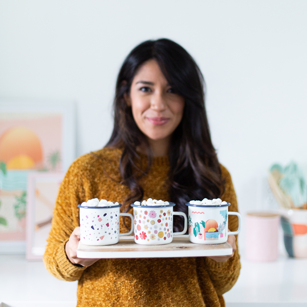 Woman holding a tray with three campfire mugs in a home setting