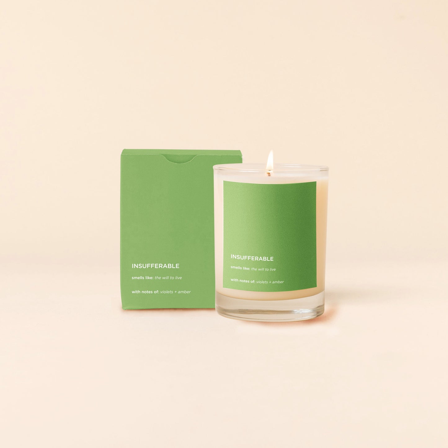 Insufferable Candle with green label and matching green packaging on a beige background