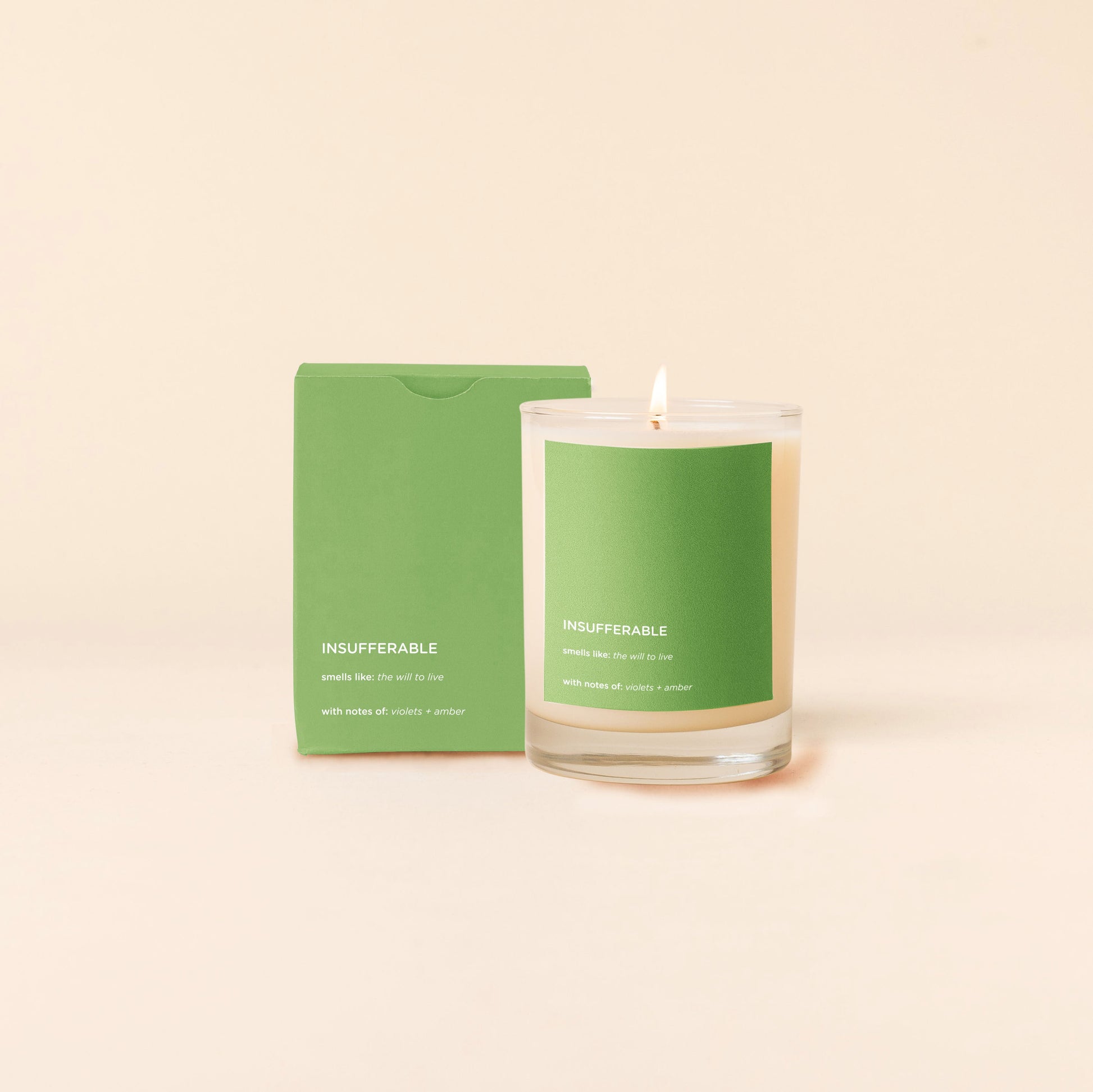 Insufferable Candle with green label and matching green packaging on a beige background
