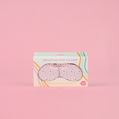 Weighted eye pillow packaging with colorful design on a pink background