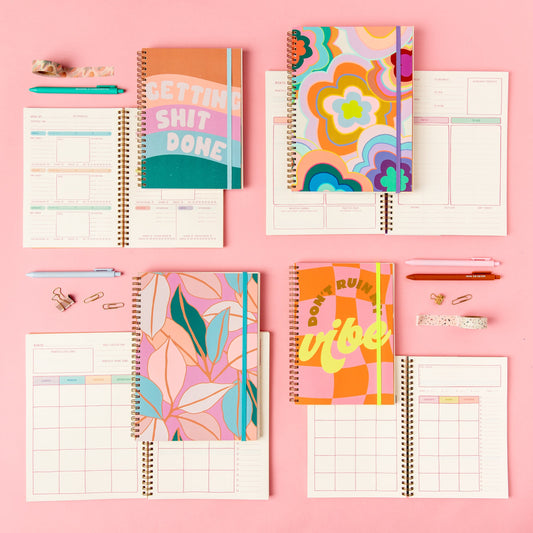 Colorful planners with various designs on a pink background