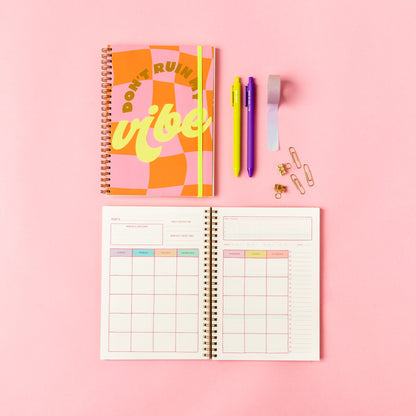 Open planner with colorful cover on a pink background