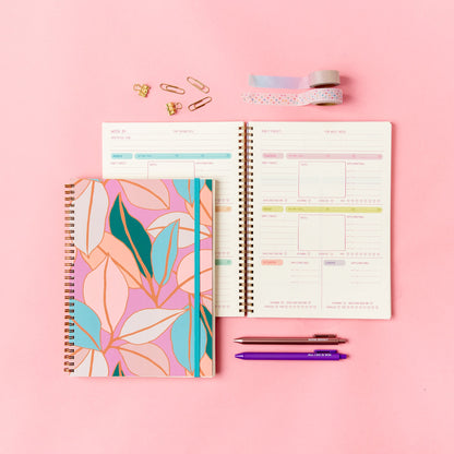 Open planner with floral cover on a pink background