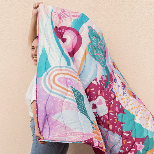 Person holding a colorful puffy blanket with abstract patterns on a beige background