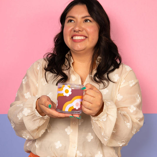 Woman holding a colorful mug against a pink and blue gradient background