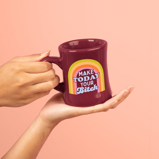 Make today your b**** Mug with colorful design and text held by a hand against a pink background