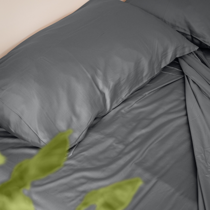 Gray bedding set with green leaves on a bed.