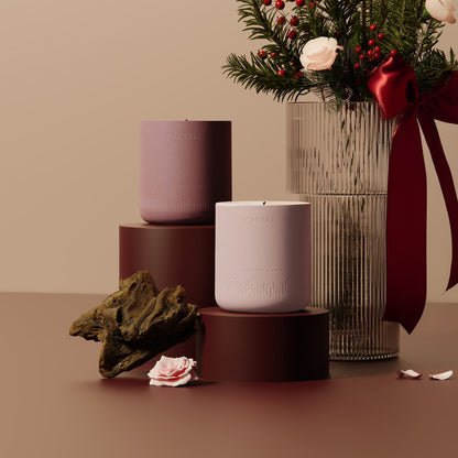 Two caftari luxurios candles on stands with a vase of flowers and decorative elements on a beige background