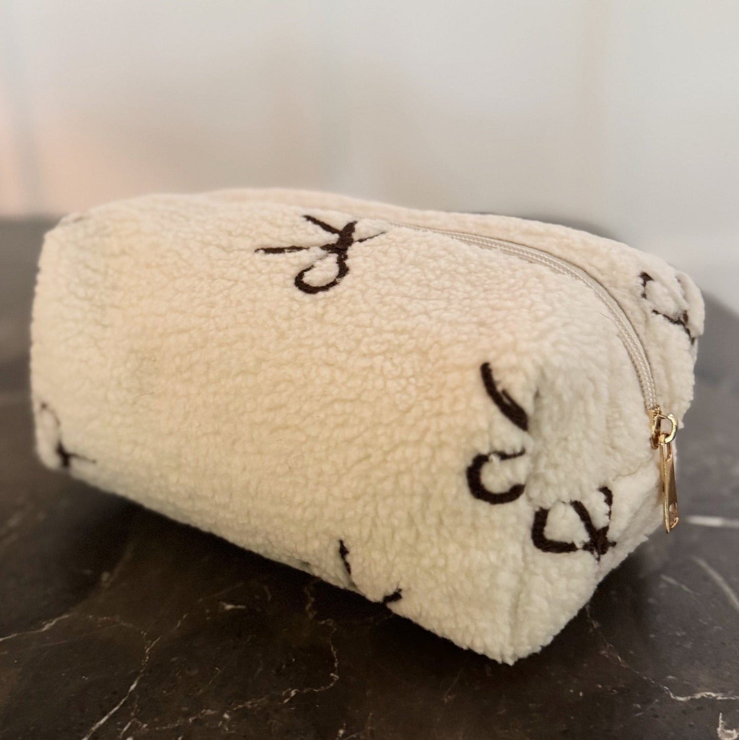 Beige pouch with black patterns on a dark surface