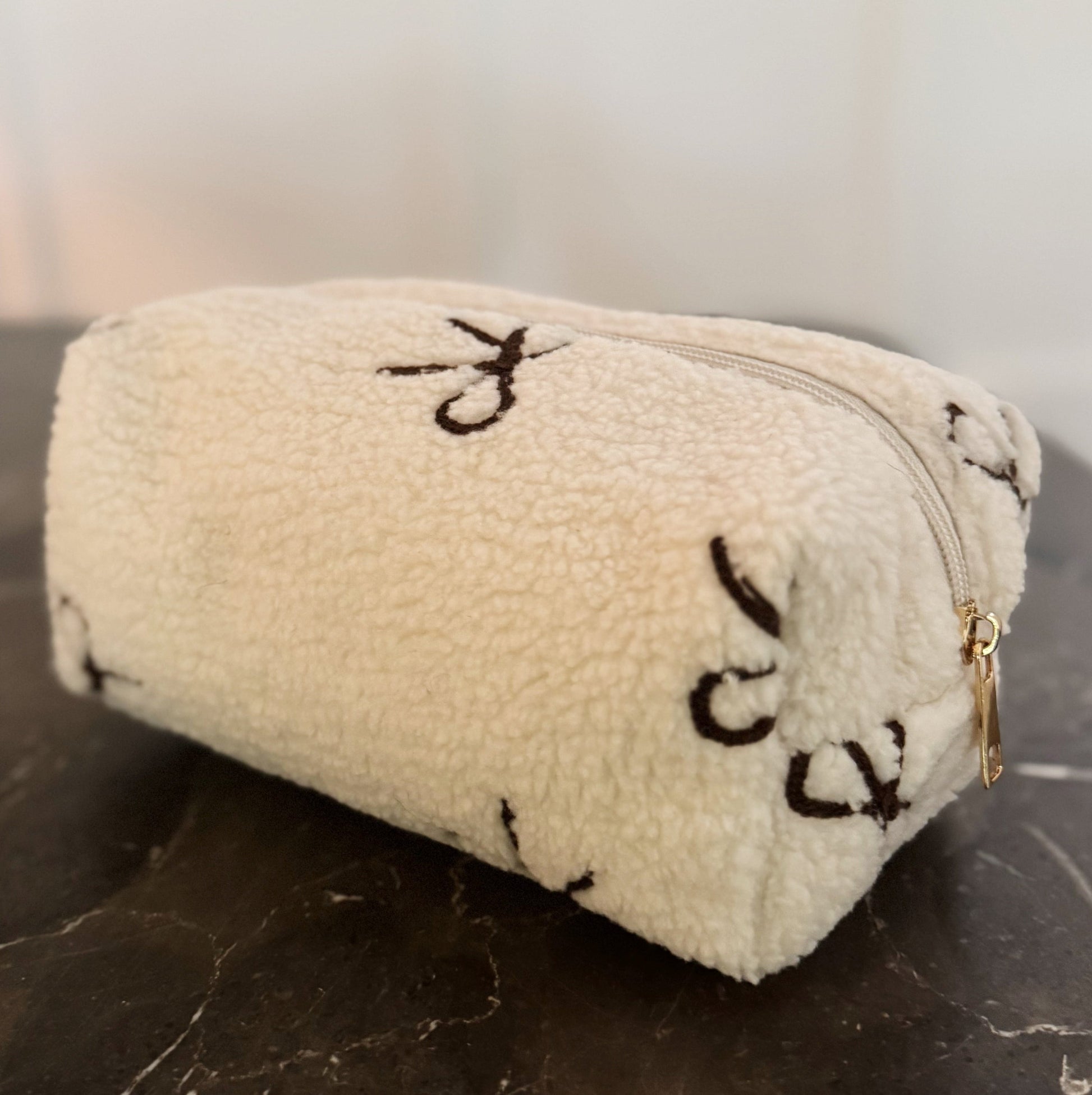 Beige pouch with black patterns on a dark surface