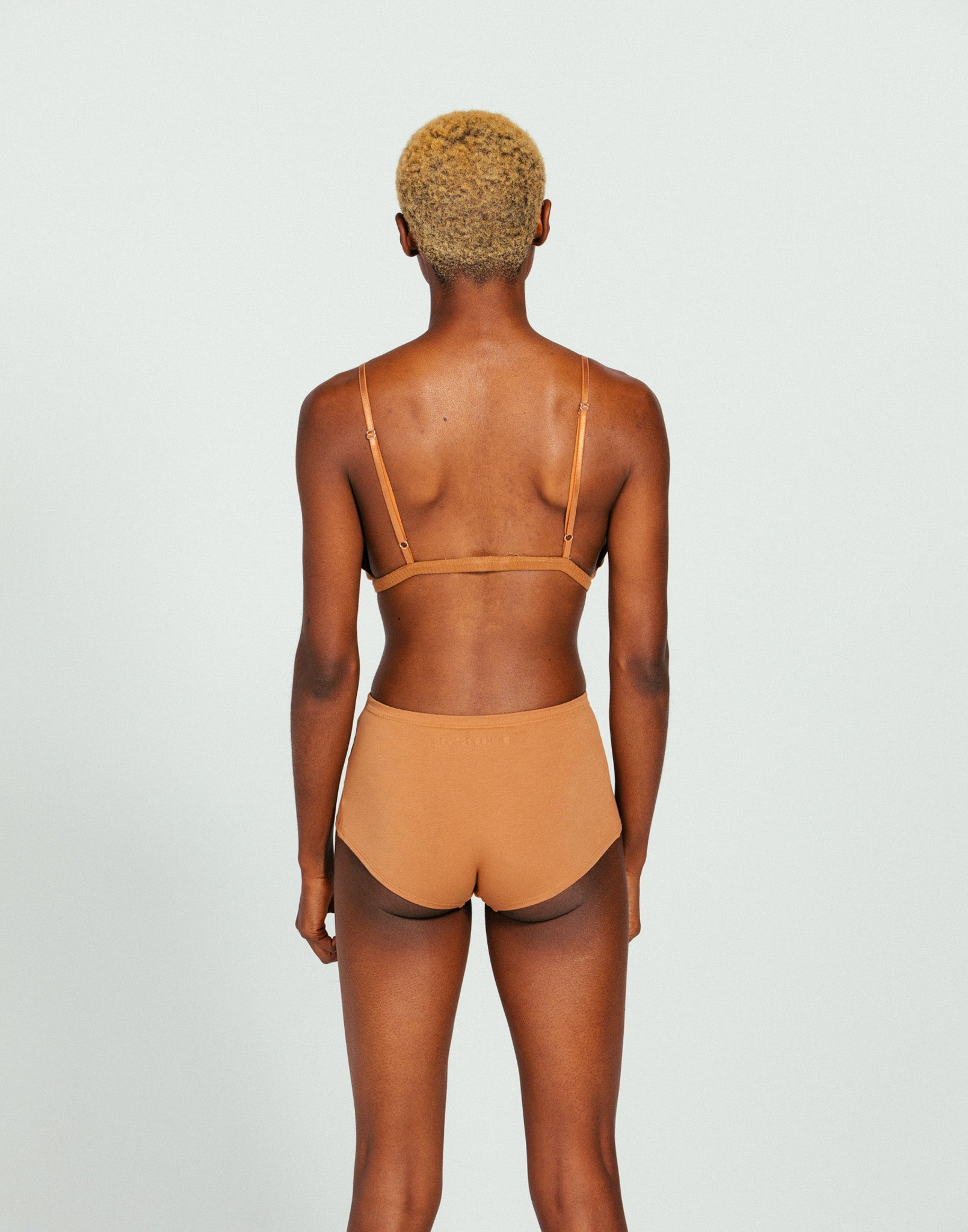 Person wearing a came organic cottong boyshort and bralette set on a plain background